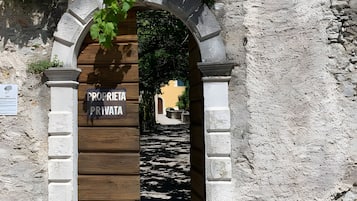 Entrada privada a una propiedad con puerta de madera y arco de piedra.