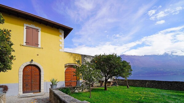 A yellow building with two wooden doors and a stone wall.