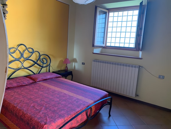 A bedroom with a bed, a window, a radiator, and a nightstand. - Apartment 'Villa Garbera' with Lakeside Dock, Private Garden and Wi-Fi (Limone Sul Garda)