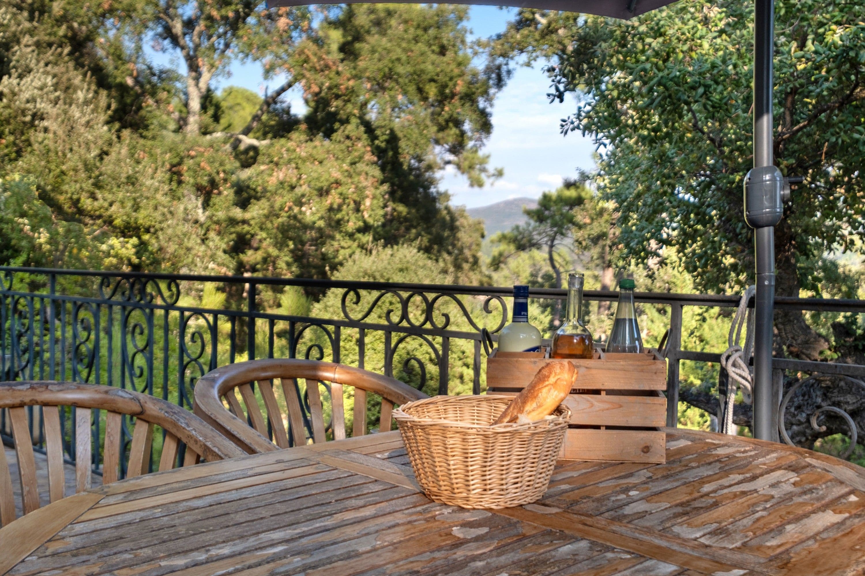 A wooden table with a wicker basket containing bread, a bottle, and a glass.