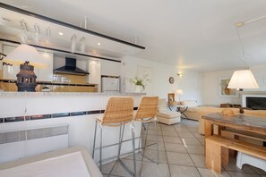 Cozinha moderna com ilha central, banquetas, mesa de jantar e lareira.