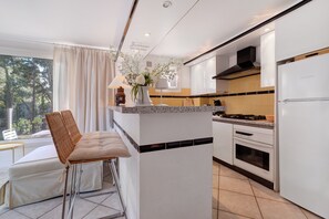 Cozinha moderna com armários brancos, uma ilha central e vista para o exterior.