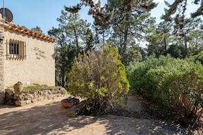 Ein Gebäude aus Stein mit Satellitenschüssel, einem vergitterten Fenster und einer Steinmauer.