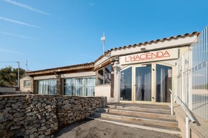 Ein Gebäude mit einem Schild, auf dem 'L'HACIENDA' steht, und einer Steinmauer davor.