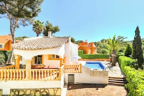 Une villa avec un toit en tuiles, une piscine et un jardin bien entretenu.