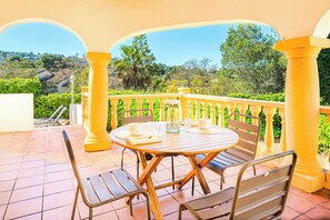 A patio with a round table and chairs, surrounded by yellow balustrades, overlooking a scenic landscape. - Villa Kiwi - Two Bedroom Villa, Sleeps 4 (El Tosalet)