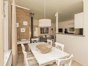 Ein stilvolles Wohnzimmer mit einem weißen Tisch, Stühlen und einer Hängeleuchte.