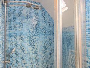Eine Dusche mit Glastür und gefliesten Wänden.