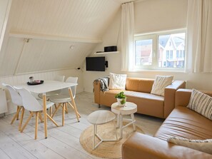 Ein gemütliches Loft mit Esstisch, Stühlen, einer Couch und einem Fernseher.