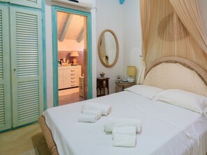 A bedroom with a bed, a bedside table, a mirror, a wardrobe, and a bathroom visible through an open door. - Holiday Home in Golfo Aranci With Bathtub (Golfo Aranci)