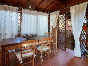 A wooden dining table with chairs, a bowl, and a hanging light fixture. - Holiday Home in Golfo Aranci With Bathtub (Golfo Aranci)