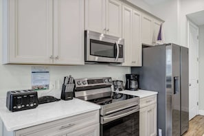 A modern kitchen with stainless steel appliances, including a microwave, oven, and refrigerator. There is a coffee maker and a toaster on the counter. - Lemon Tide Cottage | Private Pool + Margaritaville & Waterpark Access - 2914SR (Kissimmee)