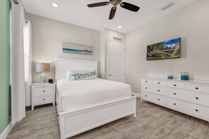 A bedroom with a bed, a nightstand, a dresser, a ceiling fan, a painting, and a door. - Lemon Tide Cottage | Private Pool + Margaritaville & Waterpark Access - 2914SR (Kissimmee)