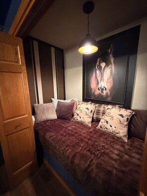 Una habitació amb un llit, un armari de fusta i un quadre de cavalls penjat a la paret.