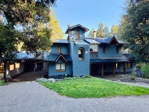 Ein zweistöckiges Haus mit einem steilen Satteldach, zahlreichen Fenstern und einem Steinfundament.