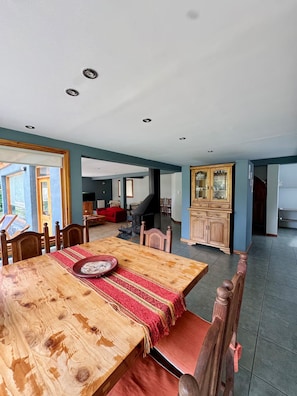 Een ruime eethoek met een houten tafel, stoelen en een loper met rode en gele strepen.