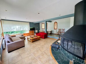 Ein Wohnzimmer mit Kamin, einer Couch, einem roten Sessel und einem Fernseher.
