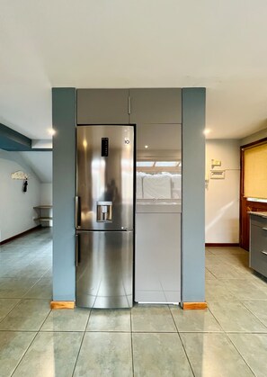 A kitchen with a stainless steel refrigerator, a sink, and a tiled floor. - Amplia casa en Bosque Patagónico para 8 (Río Negro)