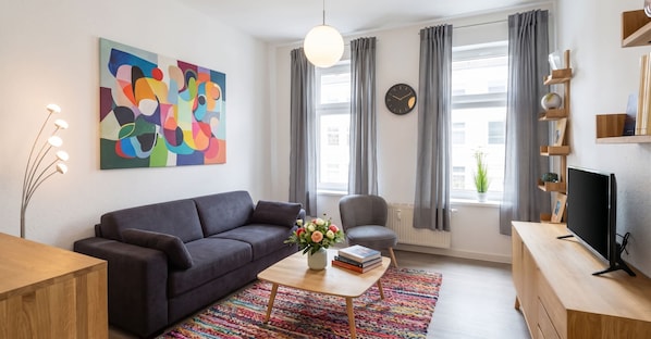 En moderne stue med sofa, sofabord og fjernsyn.