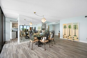 A dining area with a glass-top table, ornate chairs, and a chandelier. - Beachfront Community w/ Pool, Workout Room + Tennis - Mansions By the Sea 406B (TREASURE ISLAND)