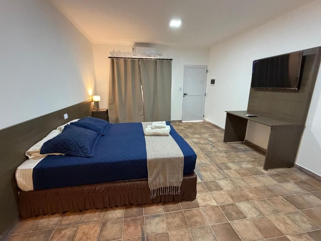 A hotel room with a bed, a desk, a television, and a door.