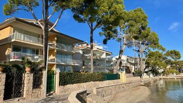A coastal building with balconies, a stone pathway, and a body of water.
