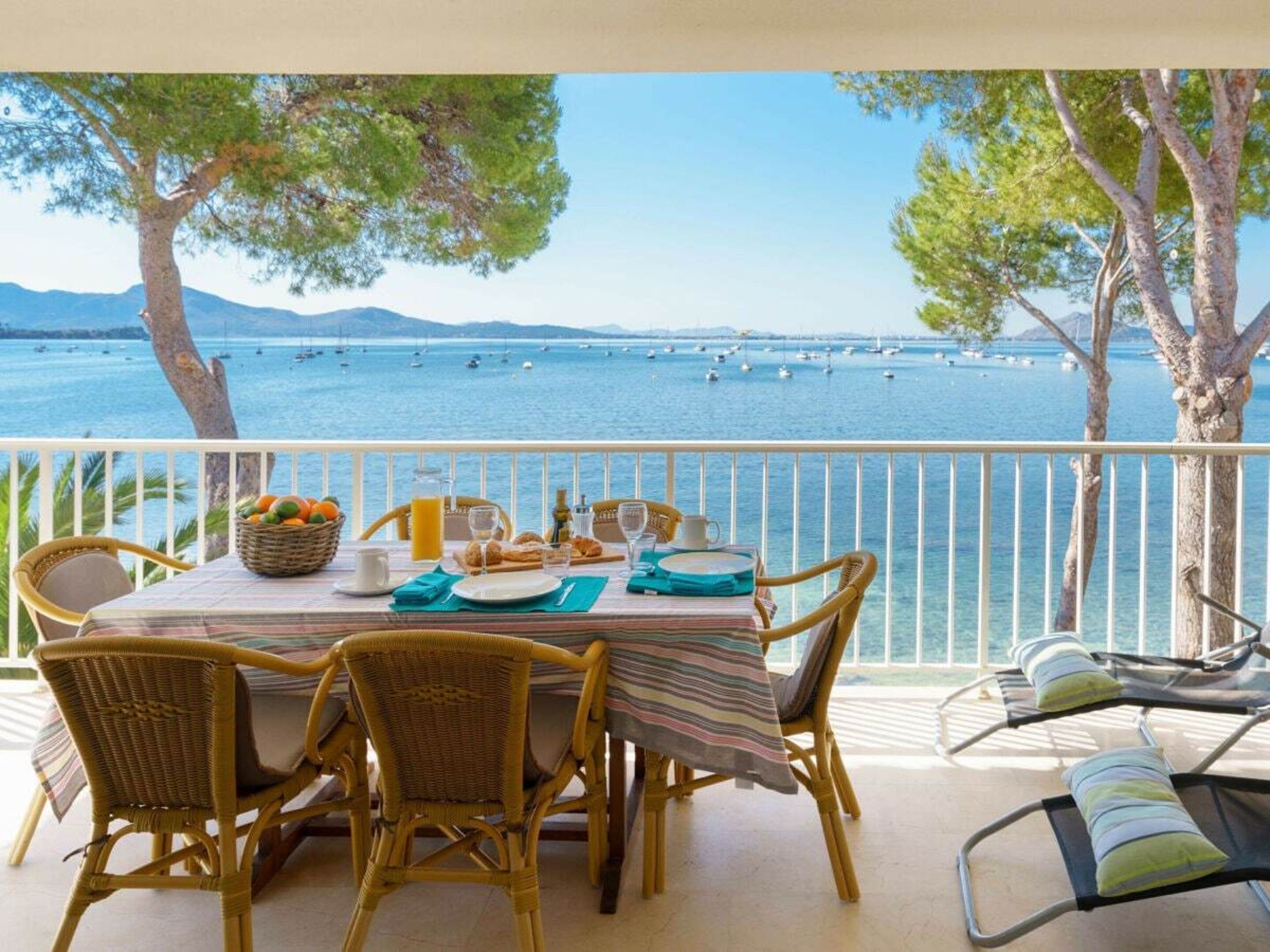 A dining area with a table set for two, overlooking a body of water with boats.