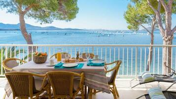 A dining area with a table set for two, overlooking a body of water with boats.