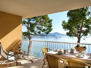 Ein Balkon mit Esstisch, der auf ein Gewässer mit Booten und Bäumen blickt.