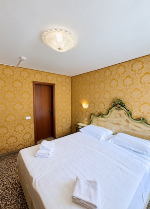 A hotel room with a bed, a door, a wall-mounted light, and a ceiling fixture. - Double Room With Canal View (Venezia)