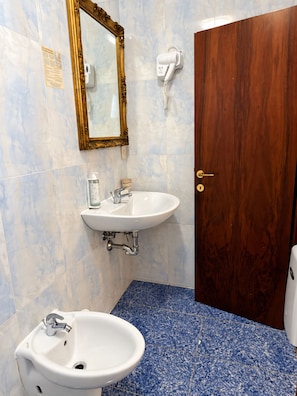 Une salle de bain équipée d’un lavabo, d’un miroir et d’un sèche-cheveux.