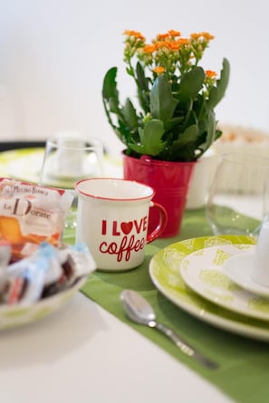 A table setting with a mug, a plate, a spoon, a glass, a packet of food, and a potted plant. - Apartment 'Doppia' with Wi-Fi and Air Conditioning (Roma)