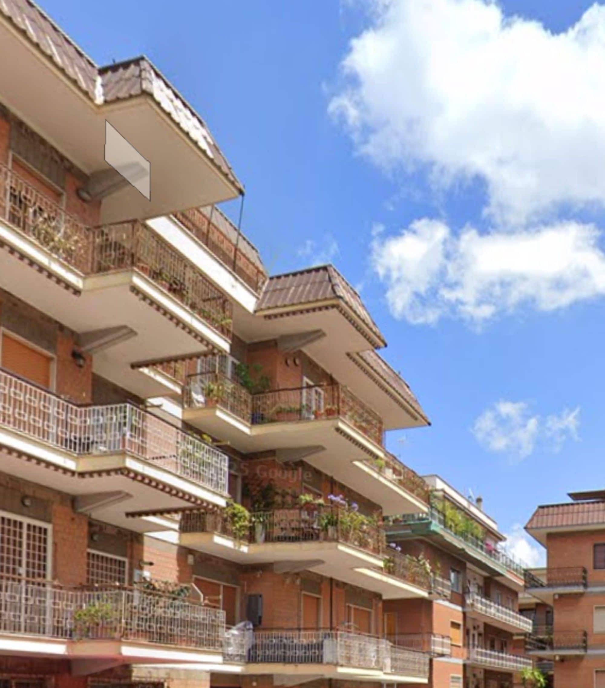 A multi-story residential building with balconies, some with plants.