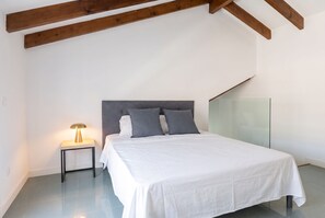 A bedroom with a bed, bedside table, lamp, and a glass partition wall. - Modern Apartment in the Cuatro Caminos Neighborhood (Madrid)
