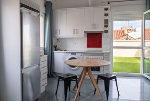 A modern kitchen with a washing machine, a dining table with stools, and a view of the outside. - Modern Apartment in the Cuatro Caminos Neighborhood (Madrid)