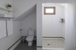 A bathroom with a toilet, a trash bin, a shower area, and a shelf with toiletries. - Modern Apartment in the Cuatro Caminos Neighborhood (Madrid)
