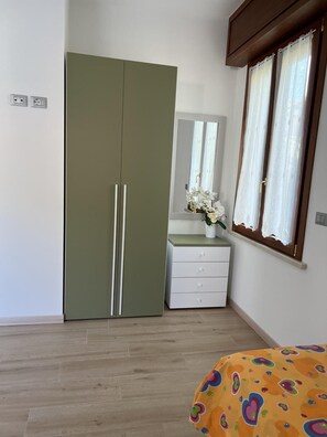 A bedroom with a wardrobe, a dresser, a mirror, and a bed. - Apartment 'Il Timone' with Wi-Fi and Air Conditioning (Toscolano Maderno)