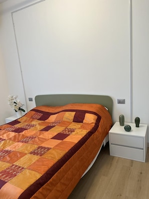 A bedroom with a bed, a nightstand, and a cactus on the nightstand. - Apartment 'Il Timone' with Wi-Fi and Air Conditioning (Toscolano Maderno)