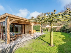 A modern house with a covered patio, a dining area, and a garden. - Holiday Home in Renesse With Swimming Pool (Renesse)