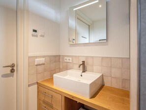 Ein Badezimmer mit Waschbecken, Holzschrank und Spiegel darüber.