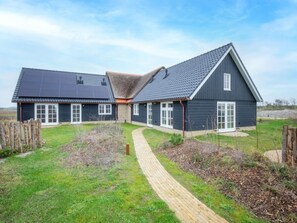 Ein zweistöckiges Haus mit gepflasterter Auffahrt und einem umzäunten Garten.