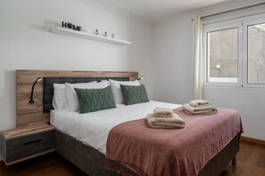 A bedroom with a bed, bedside tables, a window, and a shelf with decorative items. - Apartment in Caniço near facilities|Boeiro Living (Caniço)