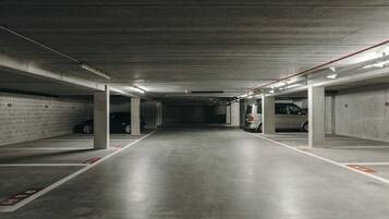 A multi-level parking garage with concrete pillars, marked parking spaces, and overhead lighting.