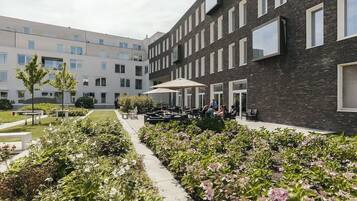 A courtyard with outdoor seating, a garden with hydrangeas, and a modern building with large windows.