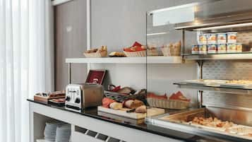 A buffet setup with various food items, including bread, pastries, and containers of yogurt.