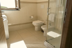 A bathroom with a toilet, a bidet, and a glass-enclosed shower area. - Elevated Home with Sea Views (Trecastagni)