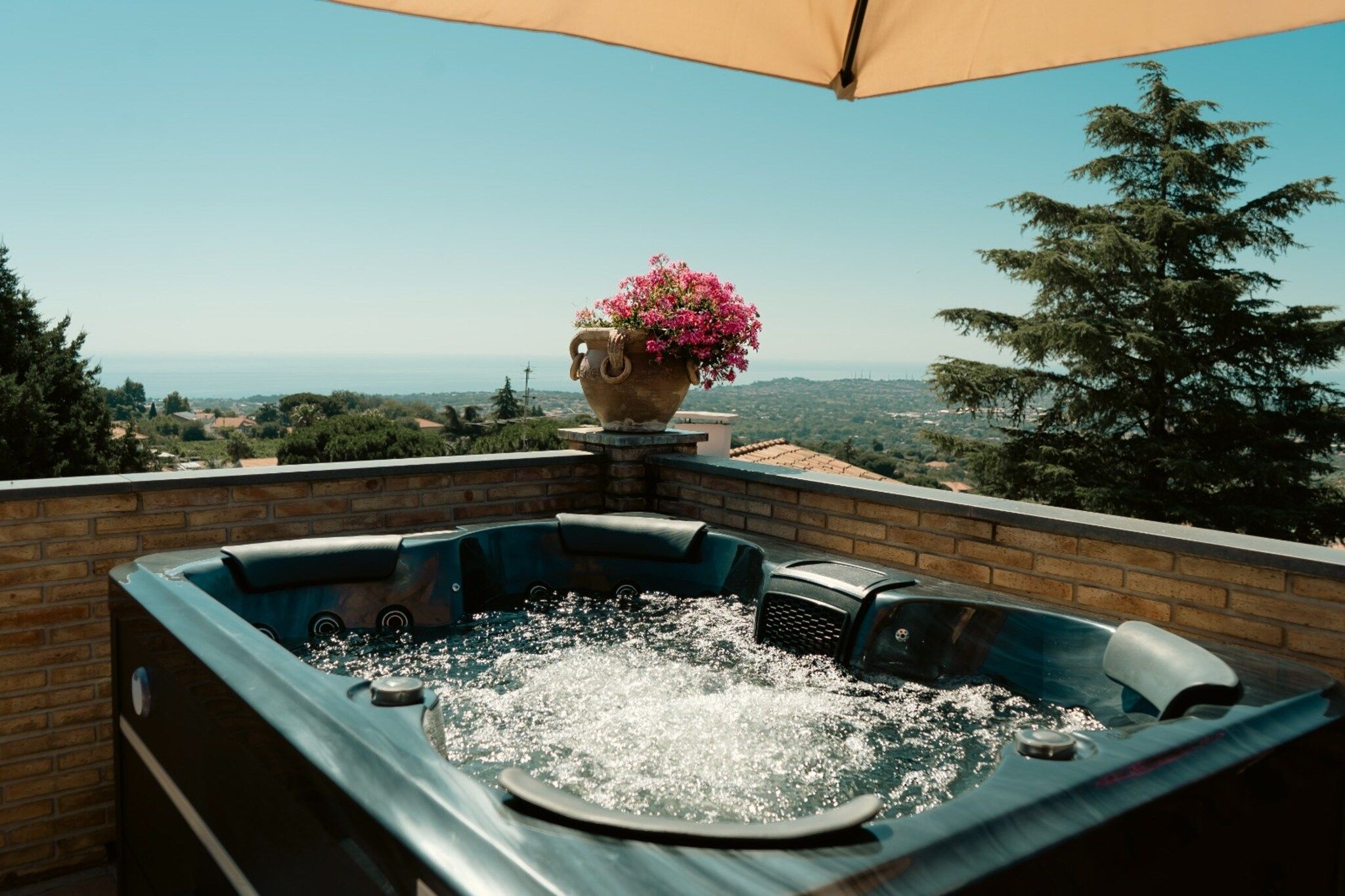 A hot tub with a view of the ocean and hills.