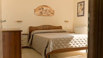 A bedroom with a wooden bed, a bedside table, a dresser, a wall-mounted artwork, and a radiator.