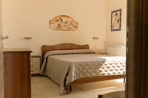 A bedroom with a wooden bed, a bedside table, a dresser, a wall-mounted artwork, and a radiator. - Elevated Home with Sea Views (Trecastagni)
