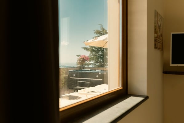A window with a view of a patio area, including a table, chairs, and a potted plant. - Elevated Home with Sea Views (Trecastagni)